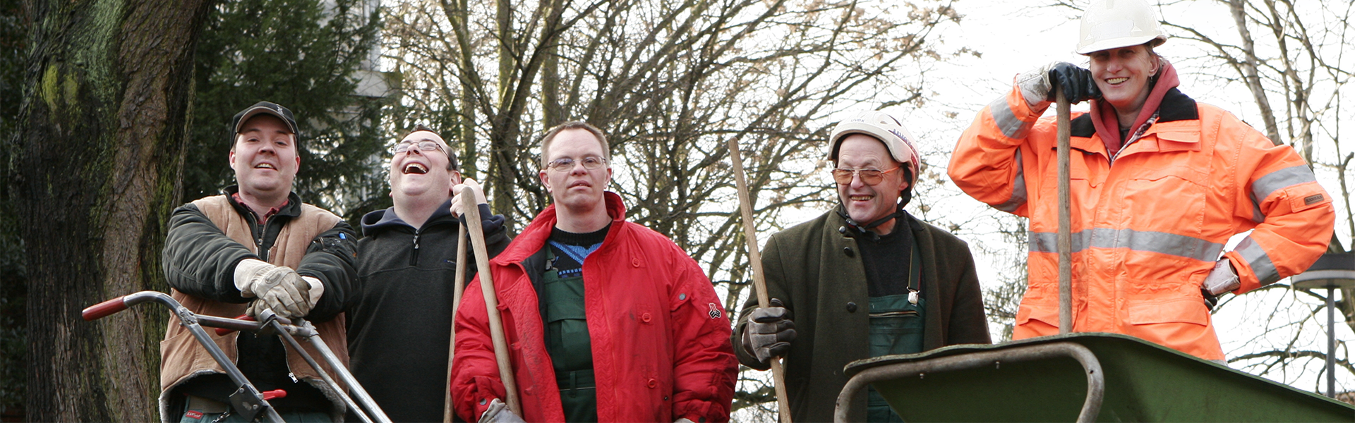 Fünf Personen der Gartengruppe der Elbe-Werkstätten mit verschiedenen Geräten bei der Arbeit im Gartenbau.