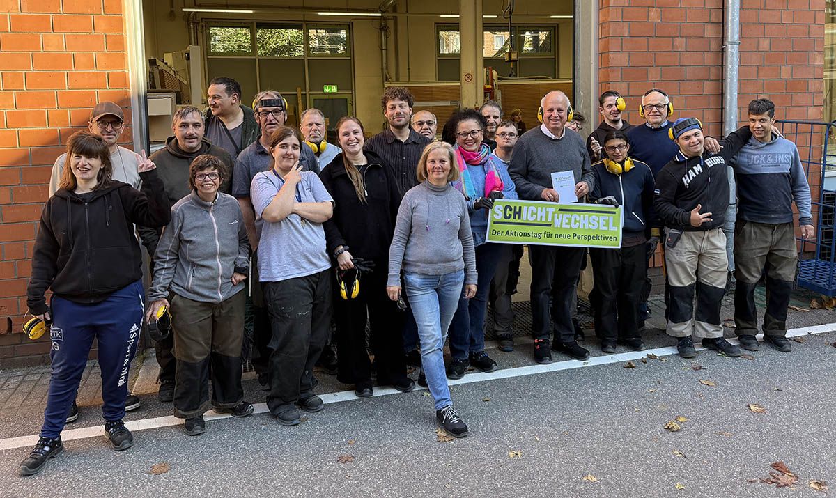 Eine Gruppe Teilnehmer posiert gemeinsam vor einer Werkshalle für ein Foto