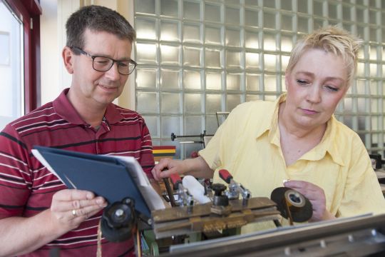 Zwei Personen der Elbe Werkstätten arbeiten an einer Buchbindemaschine.