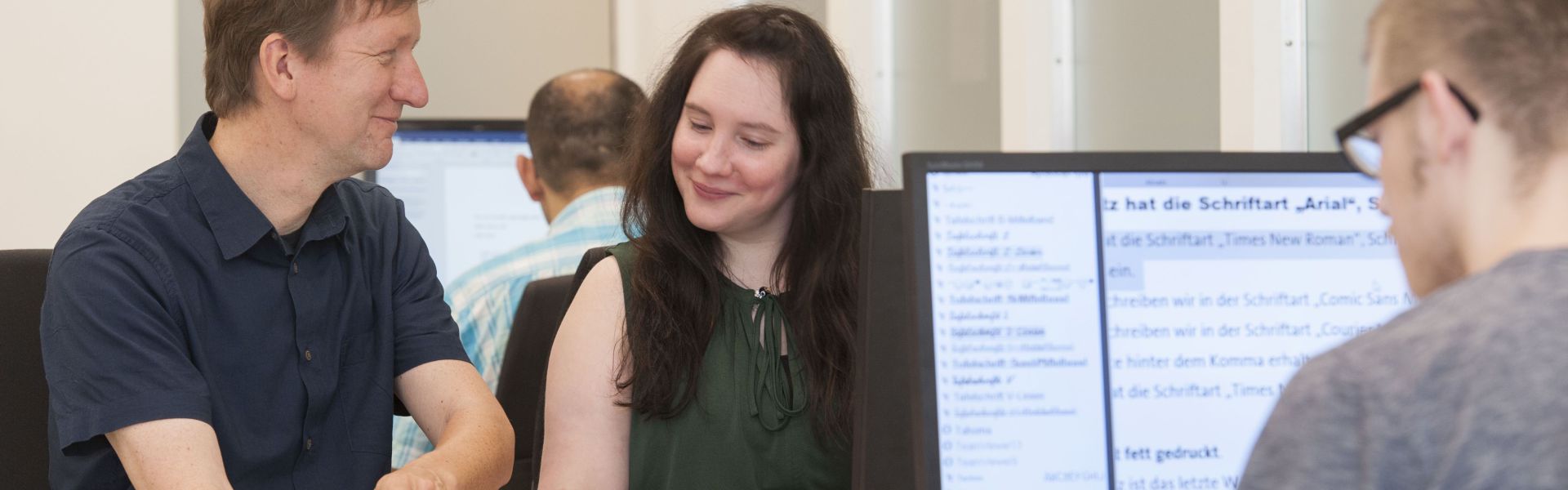 Vier Personen arbeiten im Büro am Computer.