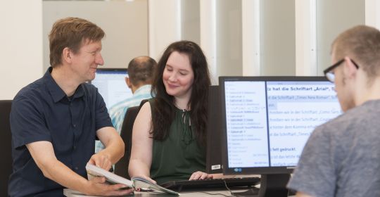 Vier Personen arbeiten im Büro am Computer.