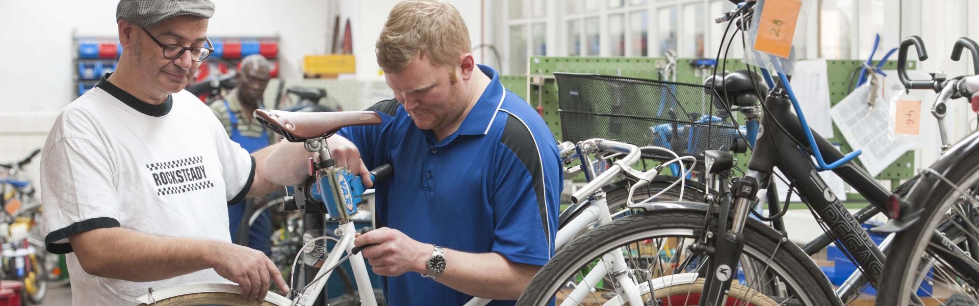 Eine Reparatur eines Rennrades durch zwei Personen in einer Werkstatt.