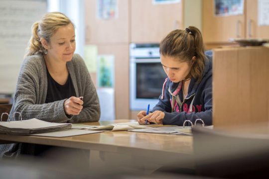Zwei Mitarbeiterinnen in einer Küche der Elbe Werkstätten, sie studieren Unterlagen auf der Küchenarbeitsfläche.