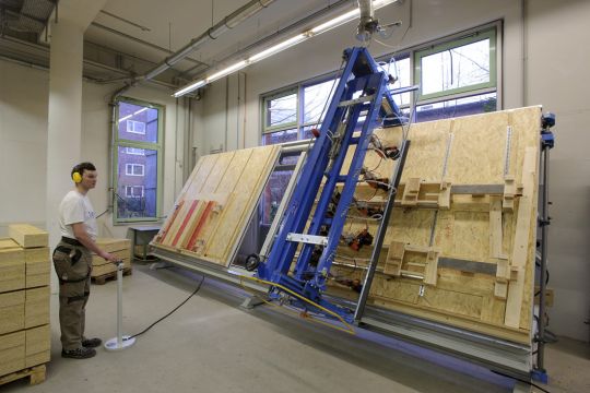 Mitarbeitender bedient eine große Produktionsmaschine für Holzpackmittel in den Elbe Werkstätten.